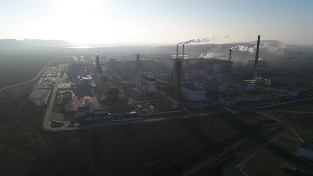 Potash plant for the extraction of potash fertilizers, mountains of waste near the plant, smoke from pipes, shooting from a height, flying up