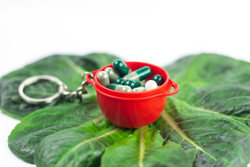 Close-up of red baby jar with dietary Supplement capsules on Romaine lettuce. Natural ingredients. Healthy vegetarian food. Organic herbs