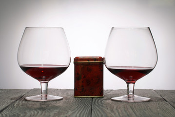 Glasses with red dry wine. Gift in a box. Stand on wooden boards. Shot in backlight.