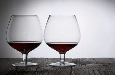 Glasses with red dry wine. Stand on wooden boards. Shot in backlight.