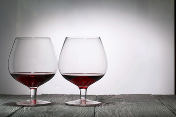 Glasses with red dry wine. Stand on wooden boards. Shot in backlight.