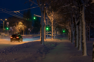 Obraz premium Moving car on a winter snowy road at night, town.