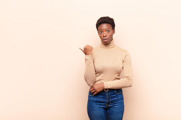 young pretty black womanlooking astonished in disbelief, pointing at object on the side and saying...