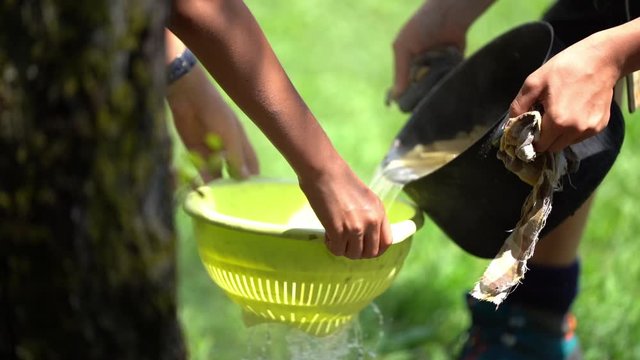Two boy scouts draining the pasta, cooking