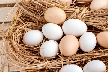 raw eggs in the hay on a wooden background