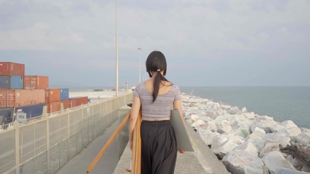 Painter with easel and coloring book walking on the pier, slow motion, CINE color/vintage