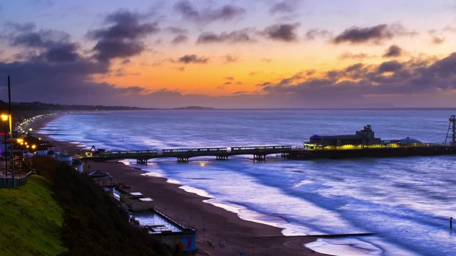 Bournemouth, UK. Aerial view of famous Pier in Bournemouth, England, UK during the sunrise. Time-lapse with moving waves of the sea, and the beach, zoom in