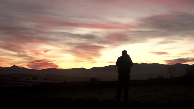 Photographer taking photographs of the sunrise while the sun rises through the mountains.Concept: Nature photographer