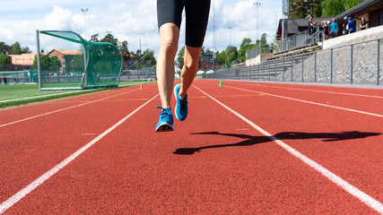 Obraz premium Sport. Woman fitness legs running on stadium. Close up of feet of a runner. Workout. Woman fitness jog workout wellness concept. Athlete runner feet running on running track.