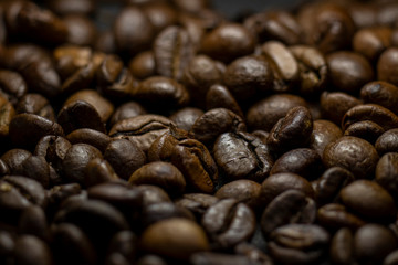 Dark background and texture of coffee beans, selective focus, closeup grains.