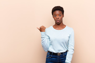 young pretty black womanlooking astonished in disbelief, pointing at object on the side and saying...