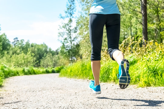 Fitness woman running at forest trail Woman fitness legs. Jogging workout wellness concept. Workout. Close up of woman athlete legs in park on sunny day. Sport Girl running in a forest.