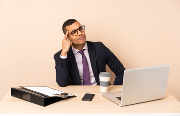 Young business man in his office with a laptop and other documents having doubts and thinking