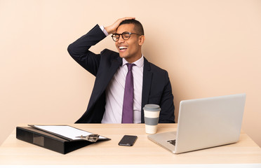 Young business man in his office with a laptop and other documents smiling a lot