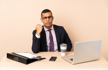Young business man in his office with a laptop and other documents with angry gesture