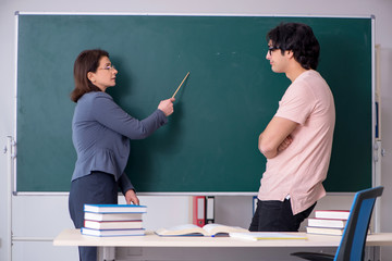 Old female teacher and male student in the classroom