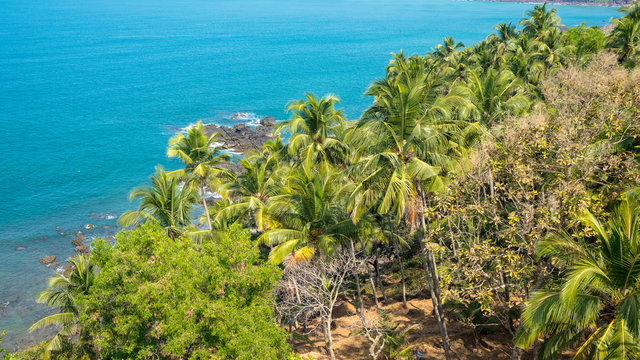 Indian ocean. Panorama of Arabian sea coast, India, Goa. View from the hight of Portuguese-built "Cabo de Rama" Fort. Amazing sand beach, colorful mountains, palm forest. Beautiful aerial view. 