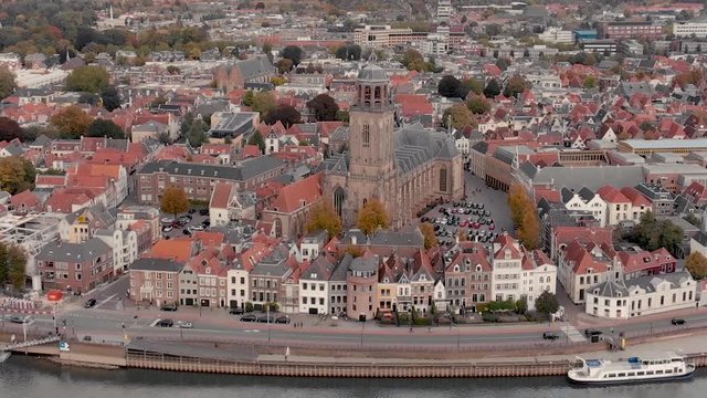 Aerial approach of cathedral church of the Dutch medieval city of Deventer at the river IJssel showing facades and rooftops of the traditional golden age houses on the waterfront boulevard