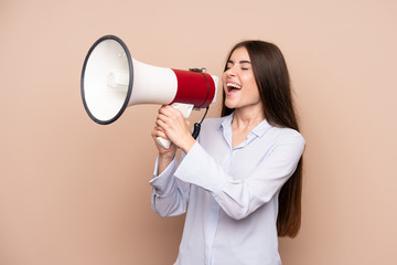 Young woman over isolated background shouting through a megaphone