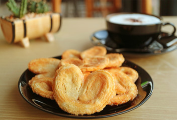 Closeup a Plate of  French Palmier Pastries with Blurry Cappuccino and Potted Plants in Background