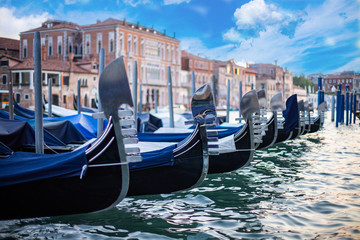 Fototapeta na wymiar Gondolas moored at the pier in Grand Canal with the view of historical buildings at Venice, Italy. Vacation concept with the view of Venice.