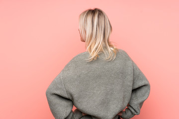 Young blonde Russian woman over isolated pink background in back position