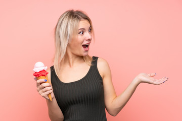 Young blonde woman with a cornet ice cream over isolated pink background with surprise facial expression