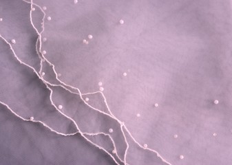Background with pink bridal veil decorated with pearl beads.