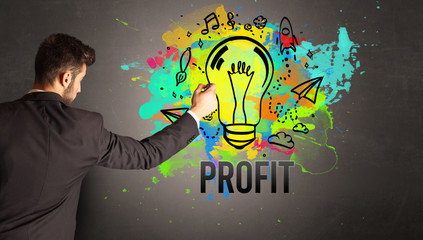 businessman drawing colorful light bulb with PROFIT inscription on textured concrete wall, new...