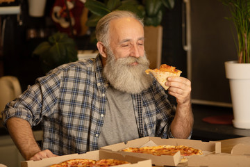 Close-up view of happy bearded senior man eating pizza