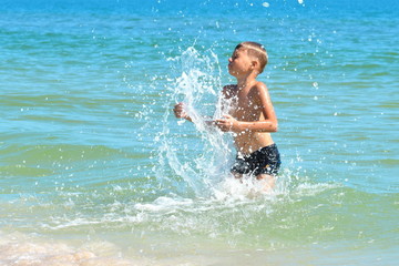 A little boy playing in the sea water. A child jumps from the sea. A tropical vacation with children.