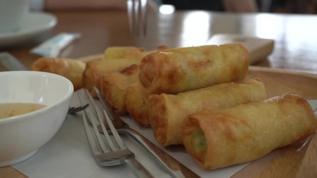 Fried Spring Rolls with dipping sauce on a wooden dish.
