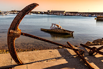 Fototapeta premium A large and rusty anchor stands a the entrance of the fishing harbor in Conil de la Frontera, Spain.