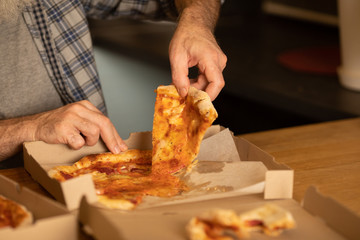 Hot pizza slice with melting cheese. Lunch or dinner delicious food italian traditional on wooden table in side view. Selective focus.