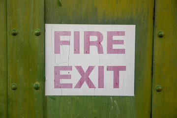 Faded fire exit sign against a gree background