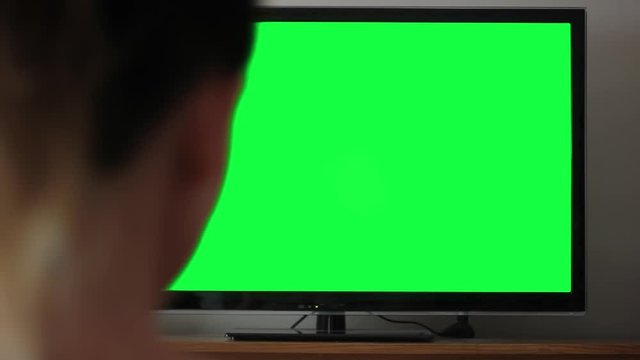 Woman Watching a TV with Green Screen at Home. 