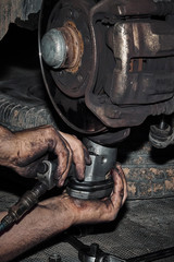 Mecánico reparando la transmisión y los frenos de un automóvil en el taller.