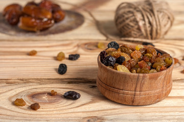 Golden and black raisins in a bowl on a light wooden background. Dried fruits.