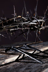 Bloody nails and crown of thorns as symbol of passion, death and resurrection of Jesus Christ. Selective focus on nails.