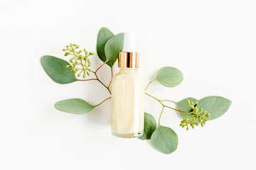 Bottle with hyaluronic acid / eucalyptus essential oil, eucalypt leaf on white background. Concept...
