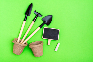 Home gardening. Miniature gardening tools: scoop, rake, inscription board and chalk, paper pots for...