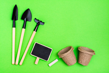 Home gardening. Miniature gardening tools: scoop, rake, inscription board and chalk, paper pots for...