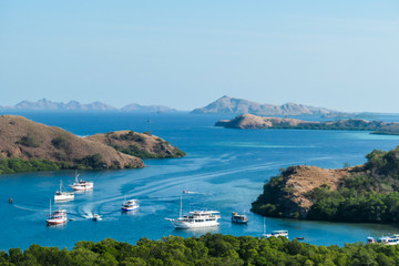 Fototapeta na wymiar A view from top of the Komodo Island in Indonesia. Discovering new places. There is a lot of boats anchored to the shores of the island's bay. Other islands in the back. Volcanic island.