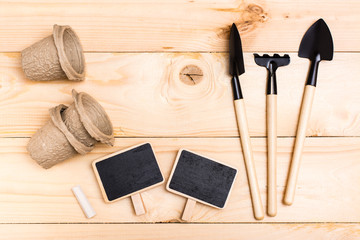 Home gardening. Miniature gardening tools: scoop, rake, inscription board and chalk on wooden...