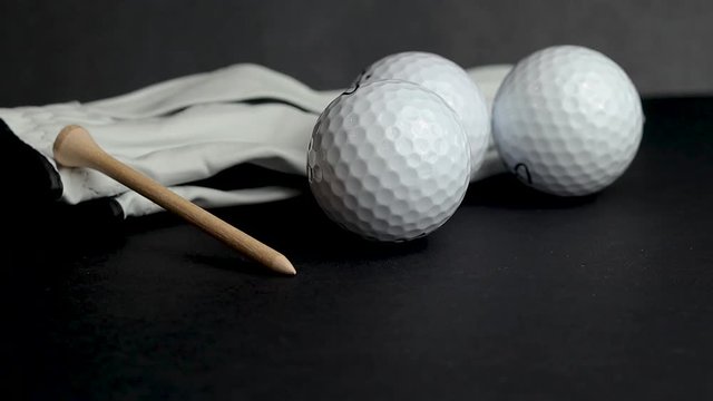 Golf ball tee&rsquo;s in front of golf balls and gloves illustrative photo shot on black studio background isolated recreational sport equipment for golf courses and leisure, hobbies and retirement. 