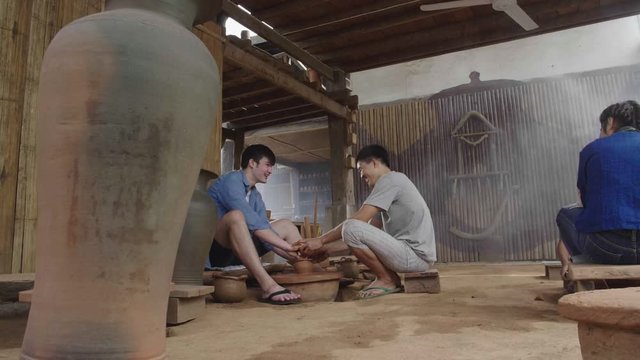 Happy Men Making Clay Objects In Pottery Workshop