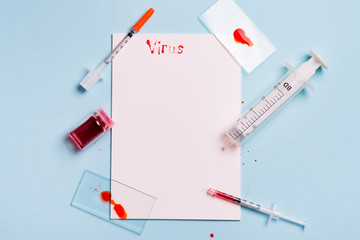 Syringes And Test Tube With Blood on a blue background with white paper and the inscription Virus