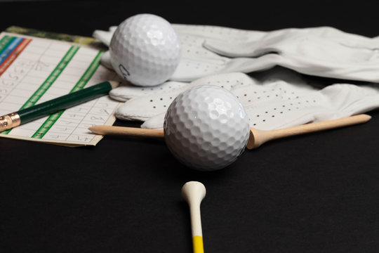 Golf ball tee’s in front of golf balls and gloves illustrative photo shot on black studio background isolated recreational sport equipment for golf courses and leisure, hobbies and retirement. 