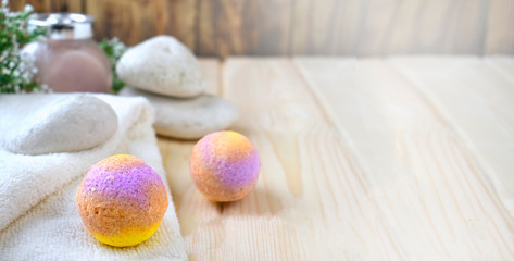 Mock up spa resort setting. Still life image with bath bombs, stones, scrub, towel on wooden background. Spring or summer relax concept.