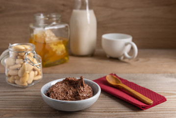 Homemade organic vegan chocolate spread, made of almonds, honey and cacao. With a jar of rice milk